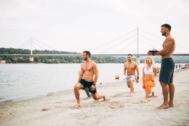 Grup Genç çekici insanlar plajda eğlenmek ve bazı fitness egzersiz yapıyor.