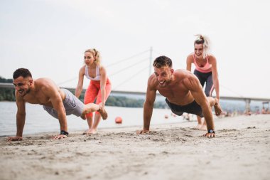 Grup Genç çekici insanlar plajda eğlenmek ve bazı fitness egzersiz yapıyor.