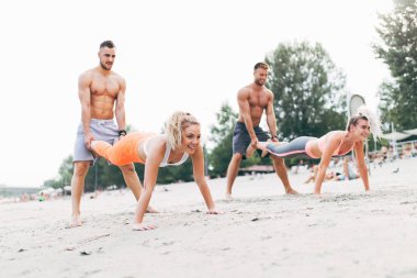 Grup Genç çekici insanlar plajda eğlenmek ve bazı fitness egzersiz yapıyor.