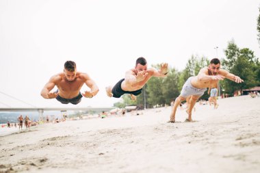 Grup Genç çekici insanlar plajda eğlenmek ve bazı fitness egzersiz yapıyor.