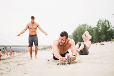 Grup Genç çekici insanlar plajda eğlenmek ve bazı fitness egzersiz yapıyor.