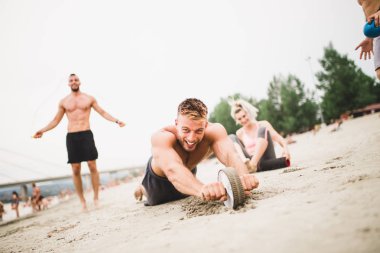 Grup Genç çekici insanlar plajda eğlenmek ve bazı fitness egzersiz yapıyor.