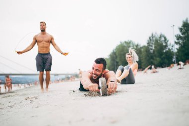Grup Genç çekici insanlar plajda eğlenmek ve bazı fitness egzersiz yapıyor.
