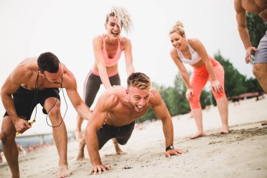 Grup Genç çekici insanlar plajda eğlenmek ve bazı fitness egzersiz yapıyor.