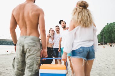 Gençlerin grup plajda piknik üzerinde zevk çekici