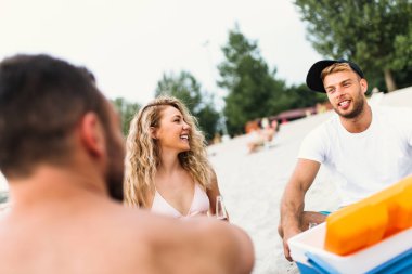 Bir grup çekici genç sahilde eğleniyor, içiyor ve kadeh kaldırıyor..