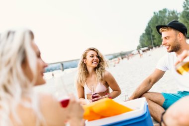 Bir grup çekici genç sahilde eğleniyor, içiyor ve kadeh kaldırıyor..