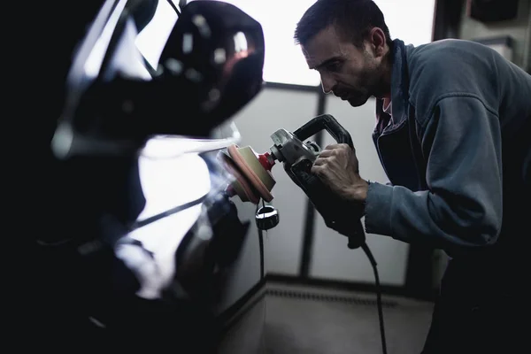 自動車修理店で軌道のポリッシャーを持つ男 選択と集中 — ストック写真