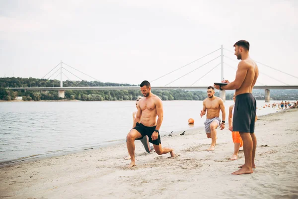 Grup Genç çekici insanlar plajda eğlenmek ve bazı fitness egzersiz yapıyor.