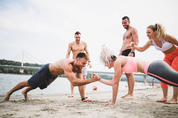 Group young attractive people having fun on beach and doing some fitness workout.