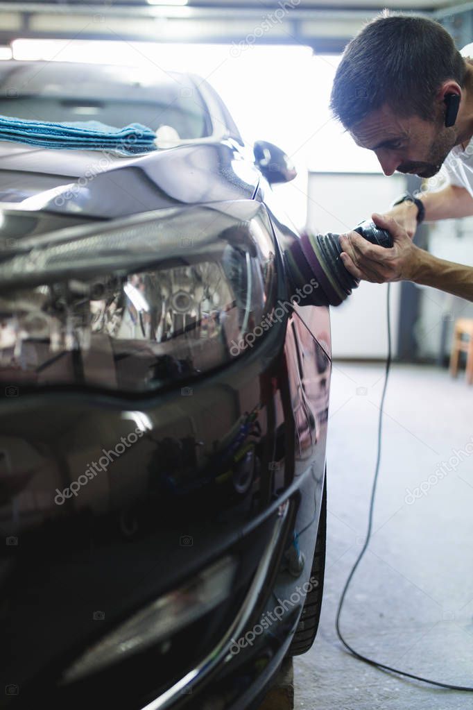 Man with orbital polisher in auto repair shop. Selective focus
