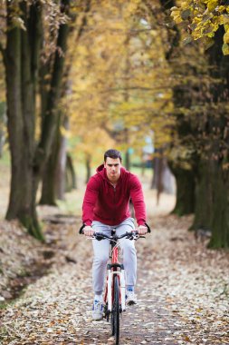 Sonbahar açık havada. Kulaklık ciddi yakışıklı adamla genç bir şehir parkı ve müzik onun bisiklet sürmek.