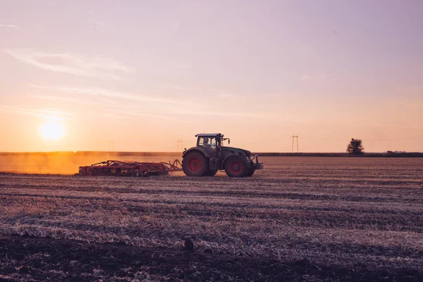 日落时拖拉机在大麦场上工作 — 图库照片
