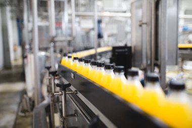 Endüstriyel fabrika kapalı ve makine. İşleme ve soda ve portakal suyu şişe şişeleme için robot fabrikası satır. Seçici odak. Kısa alan derinliği.