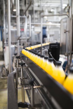 Endüstriyel fabrika kapalı ve makine. İşleme ve soda ve portakal suyu şişe şişeleme için robot fabrikası satır. Seçici odak. Kısa alan derinliği.