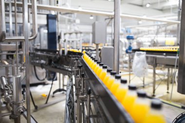Endüstriyel fabrika kapalı ve makine. İşleme ve soda ve portakal suyu şişe şişeleme için robot fabrikası satır. Seçici odak. Kısa alan derinliği.
