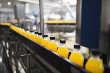 Endüstriyel fabrika kapalı ve makine. İşleme ve soda ve portakal suyu şişe şişeleme için robot fabrikası satır. Seçici odak. Kısa alan derinliği.
