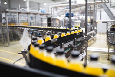 Endüstriyel fabrika kapalı ve makine. İşleme ve soda ve portakal suyu şişe şişeleme için robot fabrikası satır. Seçici odak. Kısa alan derinliği.
