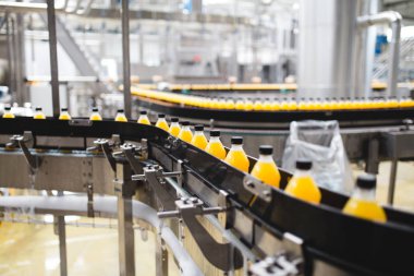 Endüstriyel fabrika kapalı ve makine. İşleme ve soda ve portakal suyu şişe şişeleme için robot fabrikası satır. Seçici odak. Kısa alan derinliği.
