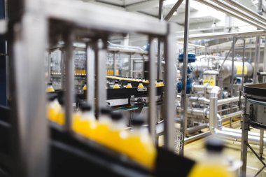 Endüstriyel fabrika kapalı ve makine. İşleme ve soda ve portakal suyu şişe şişeleme için robot fabrikası satır. Seçici odak. Kısa alan derinliği.