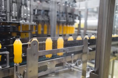 Endüstriyel fabrika kapalı ve makine. İşleme ve soda ve portakal suyu şişe şişeleme için robot fabrikası satır. Seçici odak. Kısa alan derinliği.