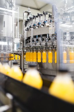 Endüstriyel fabrika kapalı ve makine. İşleme ve soda ve portakal suyu şişe şişeleme için robot fabrikası satır. Seçici odak. Kısa alan derinliği.