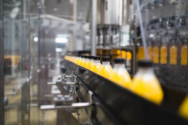 Endüstriyel fabrika kapalı ve makine. İşleme ve soda ve portakal suyu şişe şişeleme için robot fabrikası satır. Seçici odak. Kısa alan derinliği.