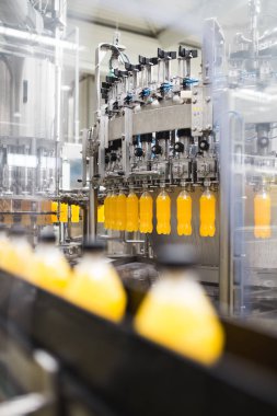 Endüstriyel fabrika kapalı ve makine. İşleme ve soda ve portakal suyu şişe şişeleme için robot fabrikası satır. Seçici odak. Kısa alan derinliği.