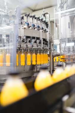 Endüstriyel fabrika kapalı ve makine. İşleme ve soda ve portakal suyu şişe şişeleme için robot fabrikası satır. Seçici odak. Kısa alan derinliği.