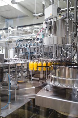Endüstriyel fabrika kapalı ve makine. İşleme ve soda ve portakal suyu şişe şişeleme için robot fabrikası satır. Seçici odak. Kısa alan derinliği.
