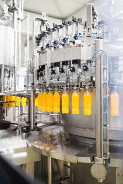 Endüstriyel fabrika kapalı ve makine. İşleme ve soda ve portakal suyu şişe şişeleme için robot fabrikası satır. Seçici odak. Kısa alan derinliği.
