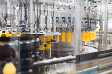 Endüstriyel fabrika kapalı ve makine. İşleme ve soda ve portakal suyu şişe şişeleme için robot fabrikası satır. Seçici odak. Kısa alan derinliği.