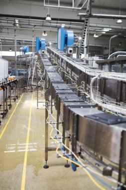 Endüstriyel fabrika kapalı ve makine. İşleme ve soda ve portakal suyu şişe şişeleme için robot fabrikası satır. Seçici odak. Kısa alan derinliği.
