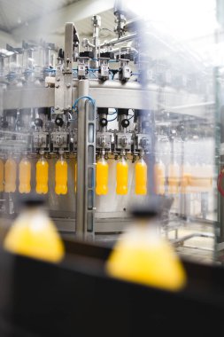 Endüstriyel fabrika kapalı ve makine. İşleme ve soda ve portakal suyu şişe şişeleme için robot fabrikası satır. Seçici odak. Kısa alan derinliği.