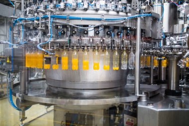 Endüstriyel fabrika kapalı ve makine. İşleme ve soda ve portakal suyu şişe şişeleme için robot fabrikası satır. Seçici odak. Kısa alan derinliği.