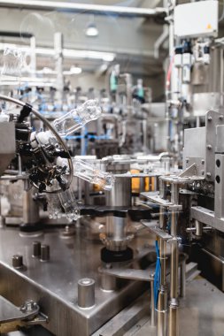 Endüstriyel fabrika kapalı ve makine. İşleme ve soda ve portakal suyu şişe şişeleme için robot fabrikası satır. Seçici odak. Kısa alan derinliği.