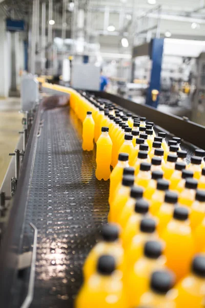 Industrial factory indoors and machinery. Robotic factory line for processing and bottling of soda and orange juice bottles. Selective focus. Short depth of field.