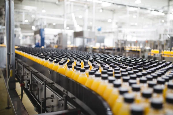 Industrial factory indoors and machinery. Robotic factory line for processing and bottling of soda and orange juice bottles. Selective focus. Short depth of field.