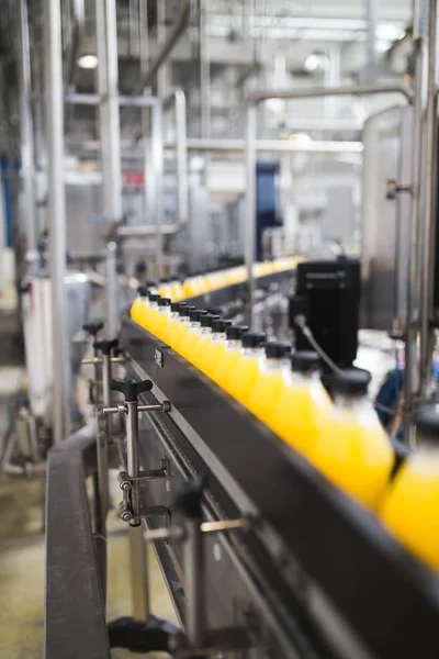 Industrial factory indoors and machinery. Robotic factory line for processing and bottling of soda and orange juice bottles. Selective focus. Short depth of field.