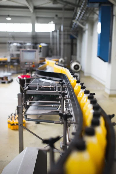 Industrial factory indoors and machinery. Robotic factory line for processing and bottling of soda and orange juice bottles. Selective focus. Short depth of field.