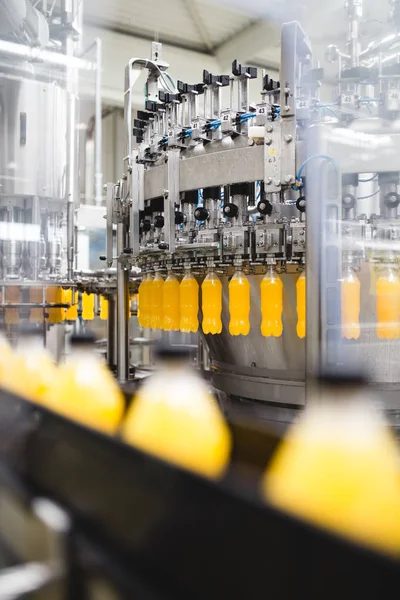 Industrial factory indoors and machinery. Robotic factory line for processing and bottling of soda and orange juice bottles. Selective focus. Short depth of field.