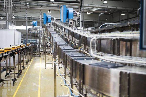 Industrial factory indoors and machinery. Robotic factory line for processing and bottling of soda and orange juice bottles. Selective focus. Short depth of field.