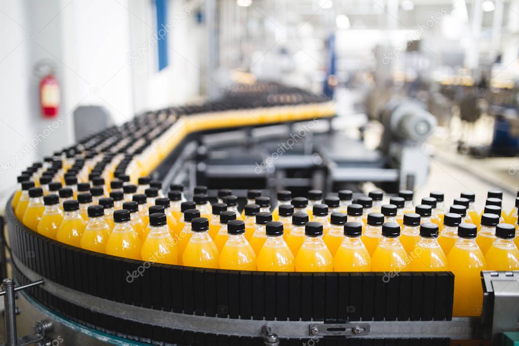 Industrial factory indoors and machinery. Robotic factory line for processing and bottling of soda and orange juice bottles. Selective focus. Short depth of field.
