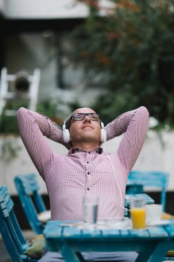 Kafe barda oturmuş, kahve içme ve müzik gözlük ile raslantı giyimli adam