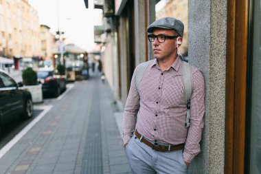 Moda retro giyimli adam kap ve şehir sokak ve müzik dinleme gözlük takıyor