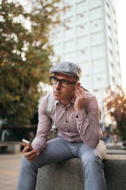 Moda retro giyimli adam şapka ve gözlük şehir sokak ve kullanma telefonla giyiyor