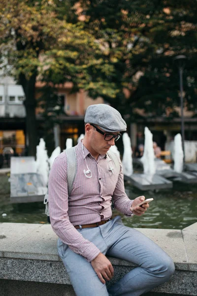 Moda retro giyimli adam şapka ve gözlük şehir sokak ve kullanma telefonla giyiyor