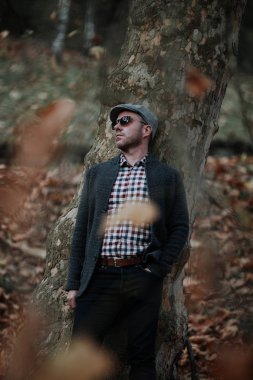 Sonbahar moda genç adam bir şapka ve güneş gözlüğü takmış açık havada portresi