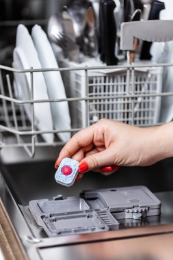 Sabun tablet bulaşık makinesi kutusuna koyarak kadın eli görüntüsünü kapatmak.