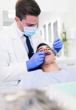 Genç ve çekici bir adam diş tedavisi görüyor. Yakın çekim..